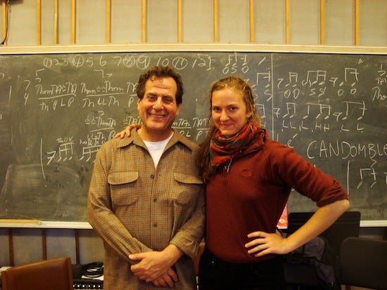 Student posing for photo with professor in front of chalboard